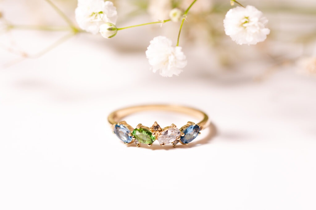 Gold band ring with 4 Stones each a blue, green, white colours with white flowers on top